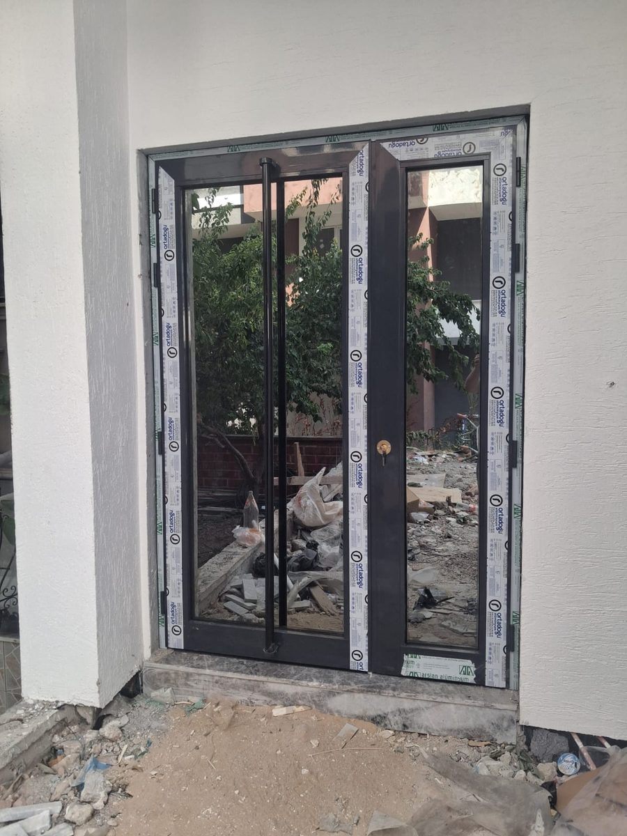 Yeni binaya takılmış antrasit renkli çift kanatlı alüminyum giriş kapısı