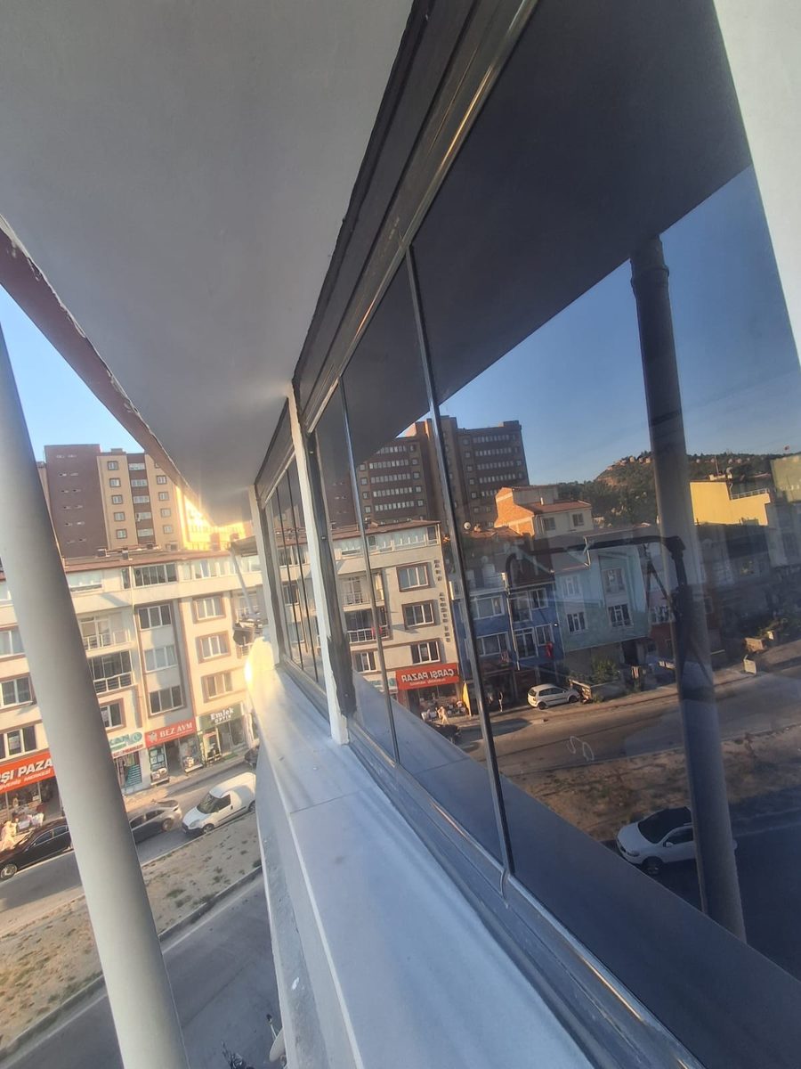 Akşam saatinde cam balkondan görünen şehir manzarası