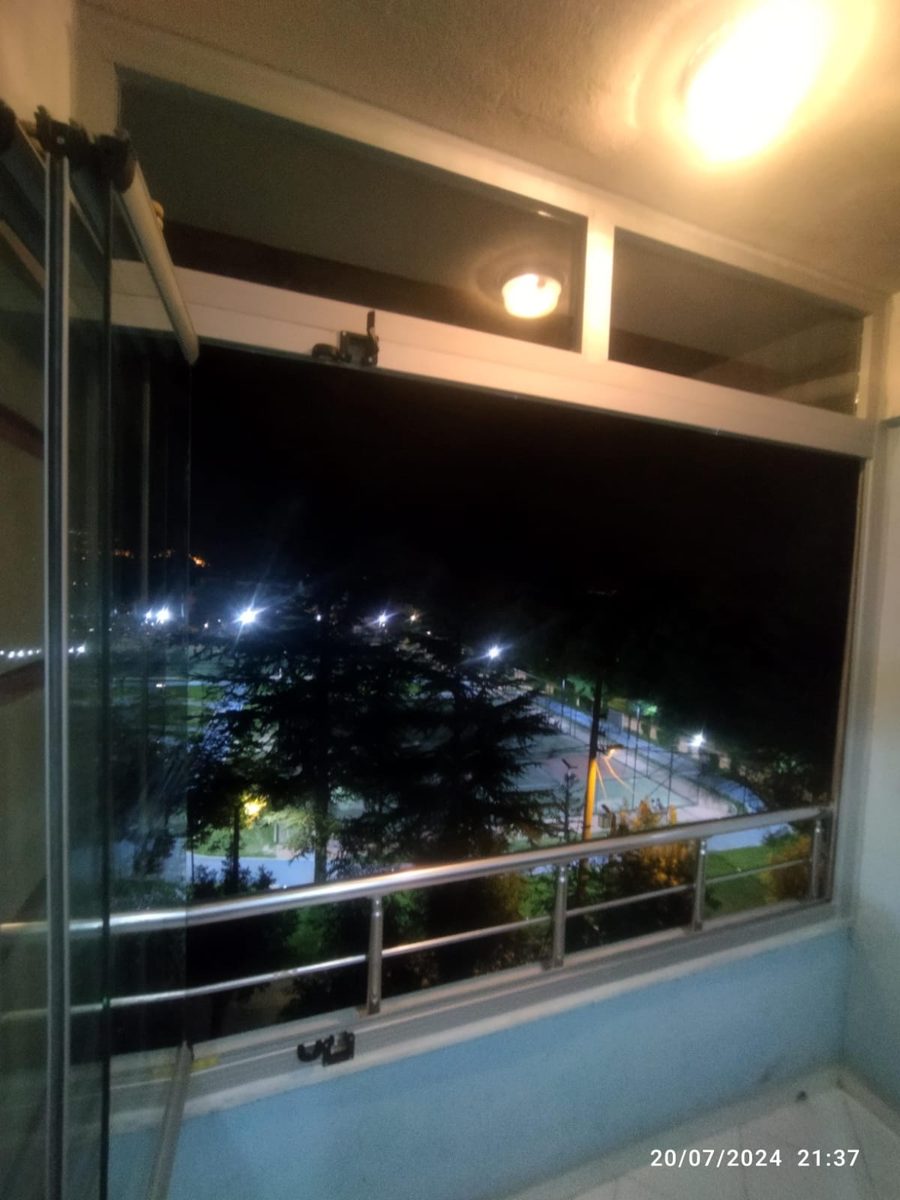 Gece aydınlatması yanan cam balkon ve dışarıdaki ağaçlar