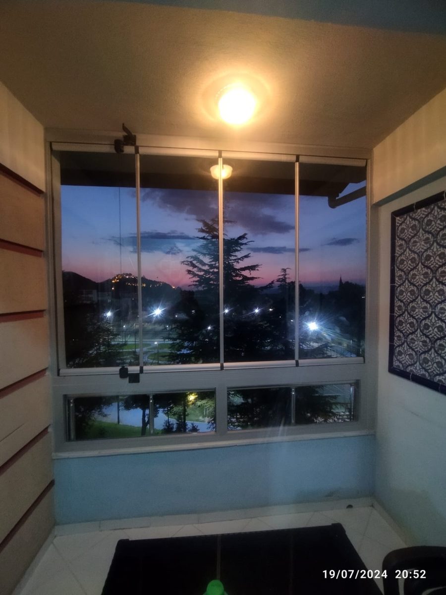 Gün batımında cam balkondan görünen gökyüzü ve ağaç