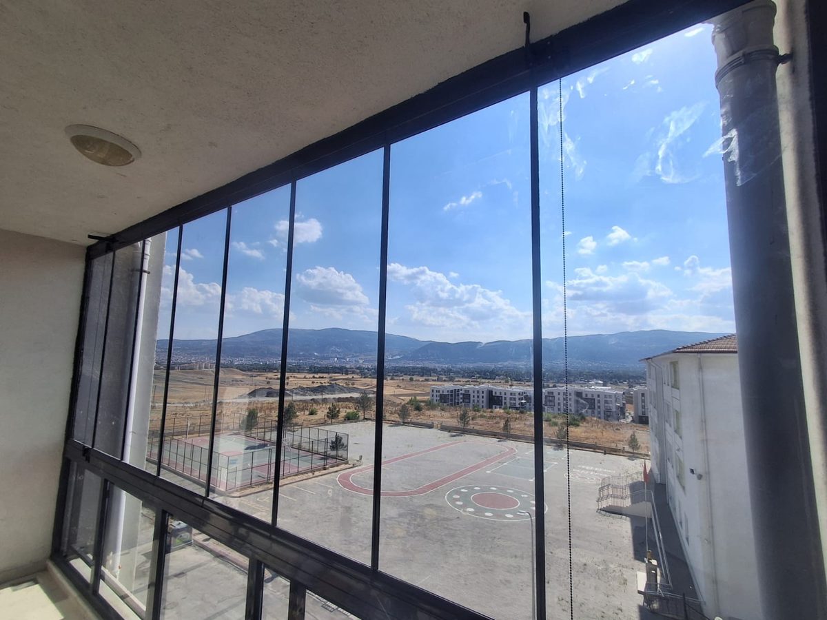 İçeriden bakıldığında geniş cam cepheli kapalı balkon ve dışarıdaki manzara