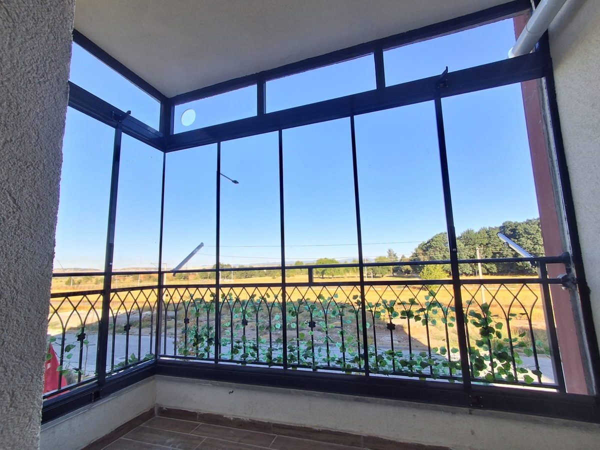 Siyah profilli cam panellerle kapatılmış köşe balkon